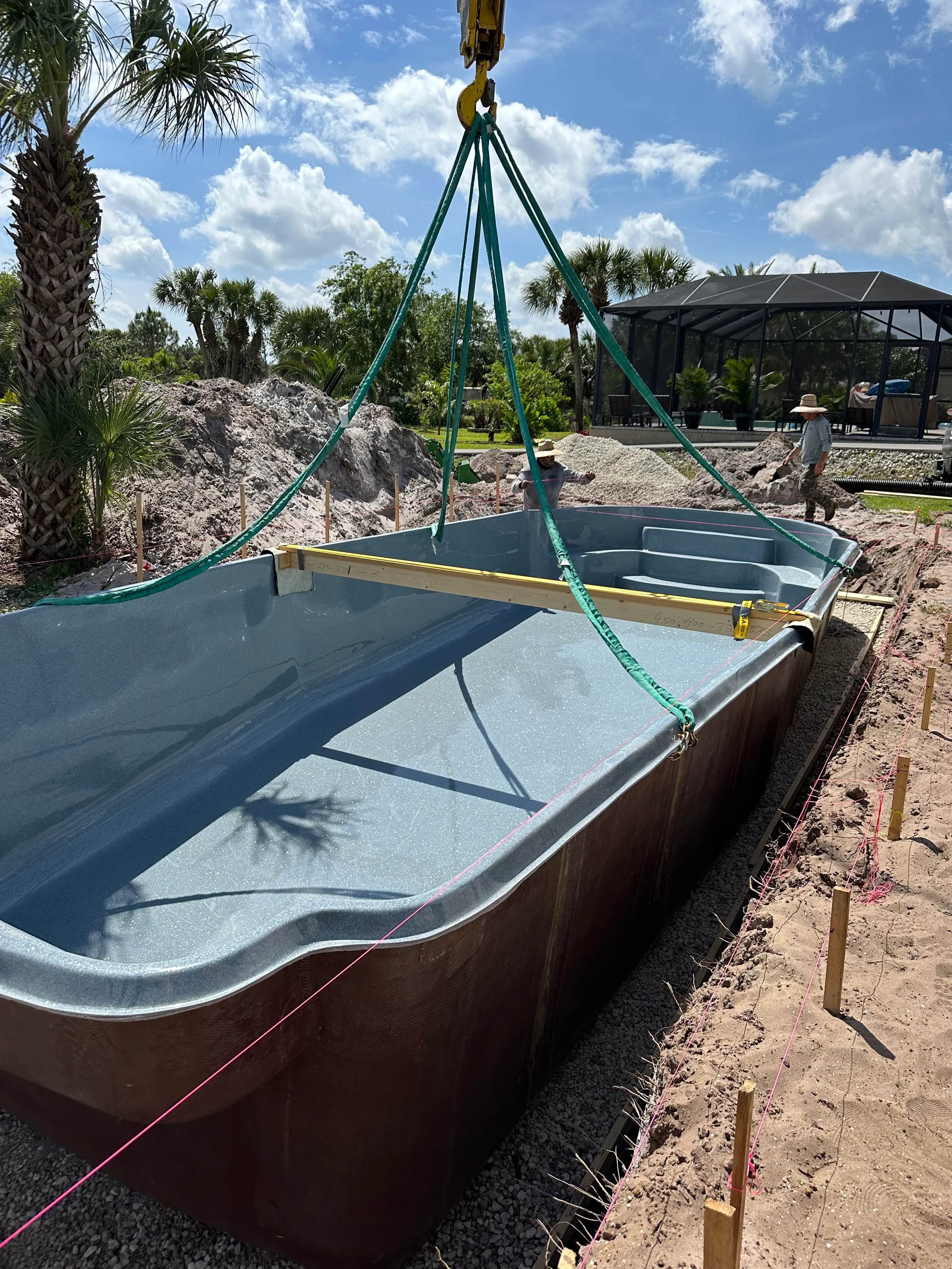 A fiberglass pool being installed by a crane