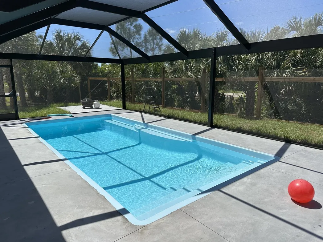 A free-form fiberglass pool at twilight with vibrant LED lighting.